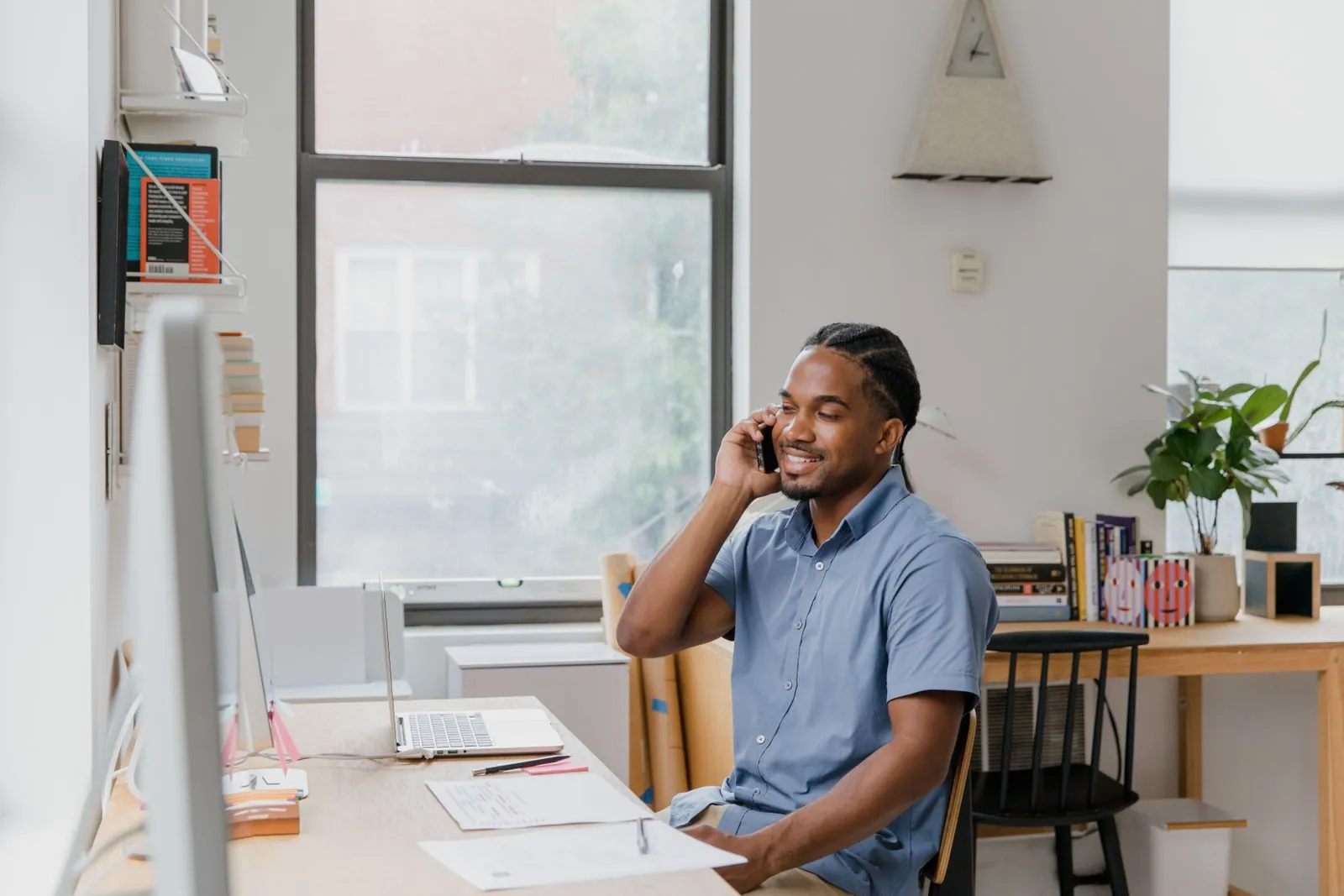 A business owner at their desk taking a customer call, laptop and order notes in front of them
