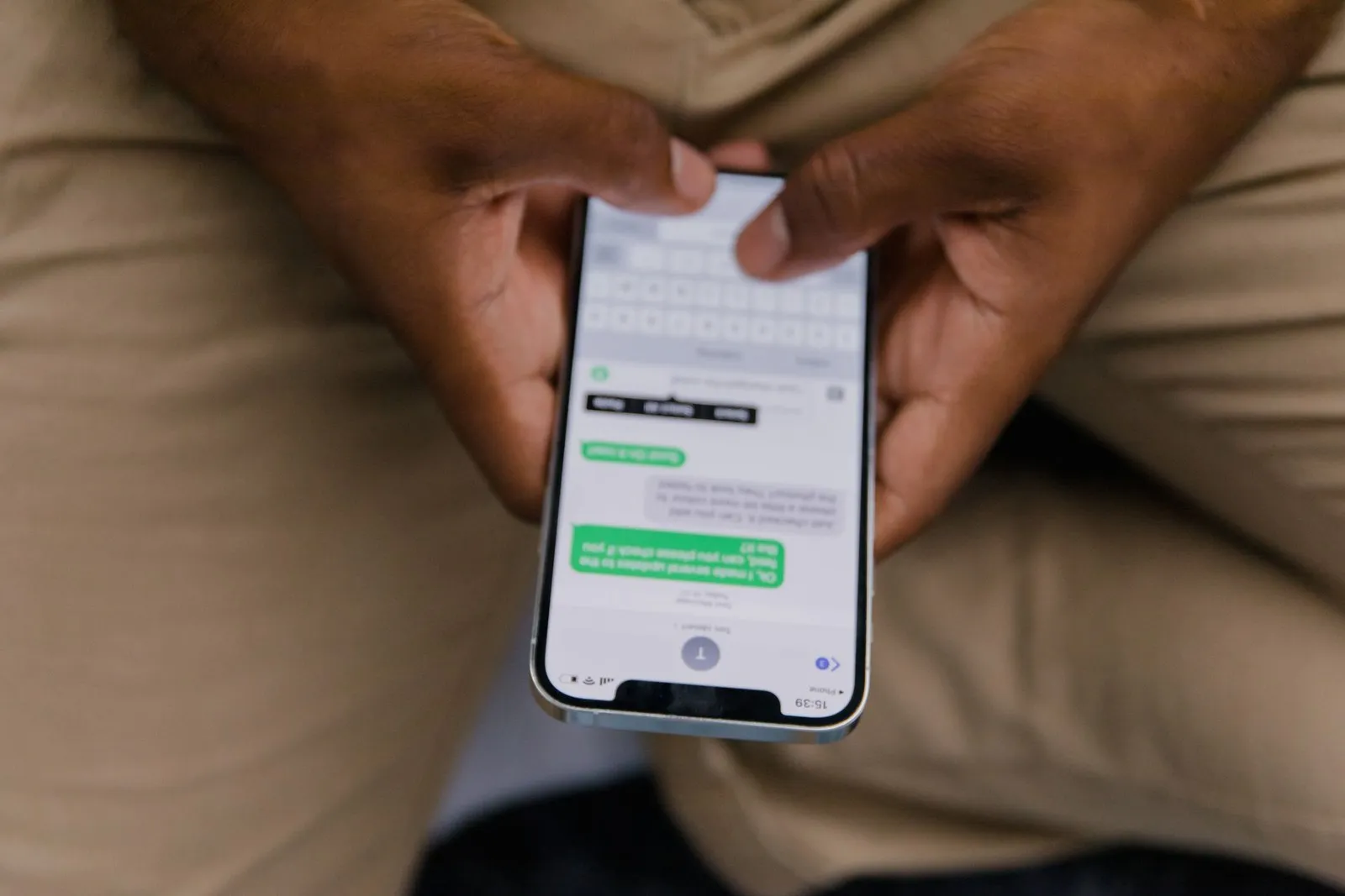 A man holding a phone open on a chat thread of sent messages with no replies
